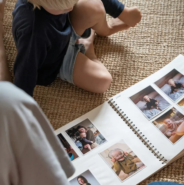 En familie har lavet en fotofremkaldelse og sidder nu på gulvet og kigger i deres fotoalbum